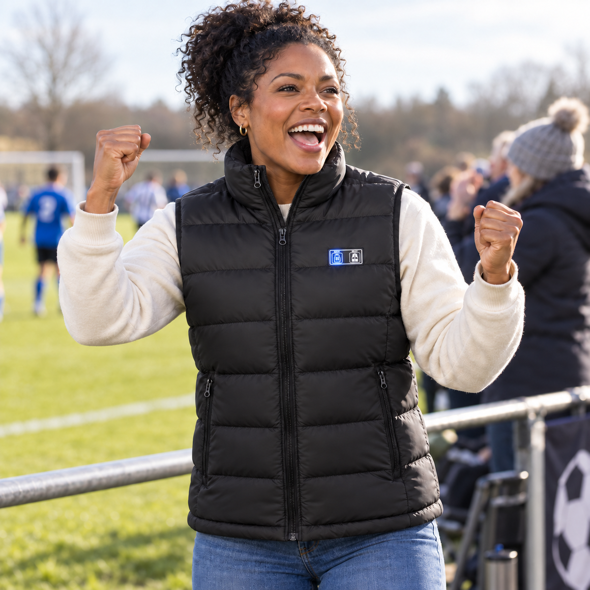 Woman cheering at a cold football touchline in the black 9-Zone Heated Gilet