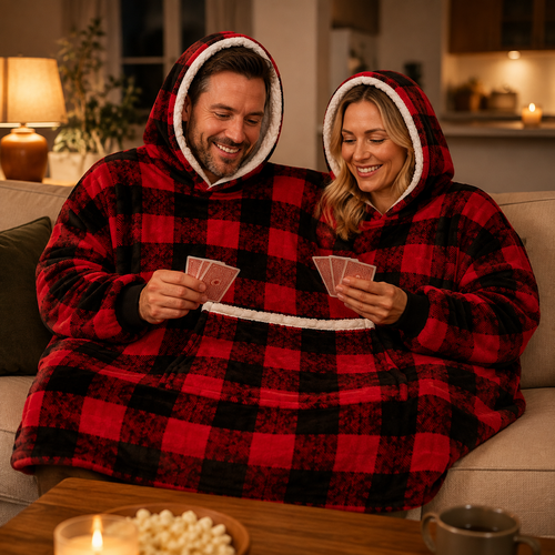 Young couple sharing the Red Plaid two-person hooded blanket while playing cards